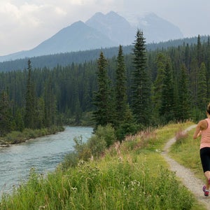 A woman running on a trail run through a scenic area near Banff.