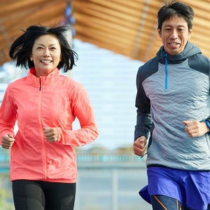 Japanese sportsman and sportswoman running together on track in a stadium.