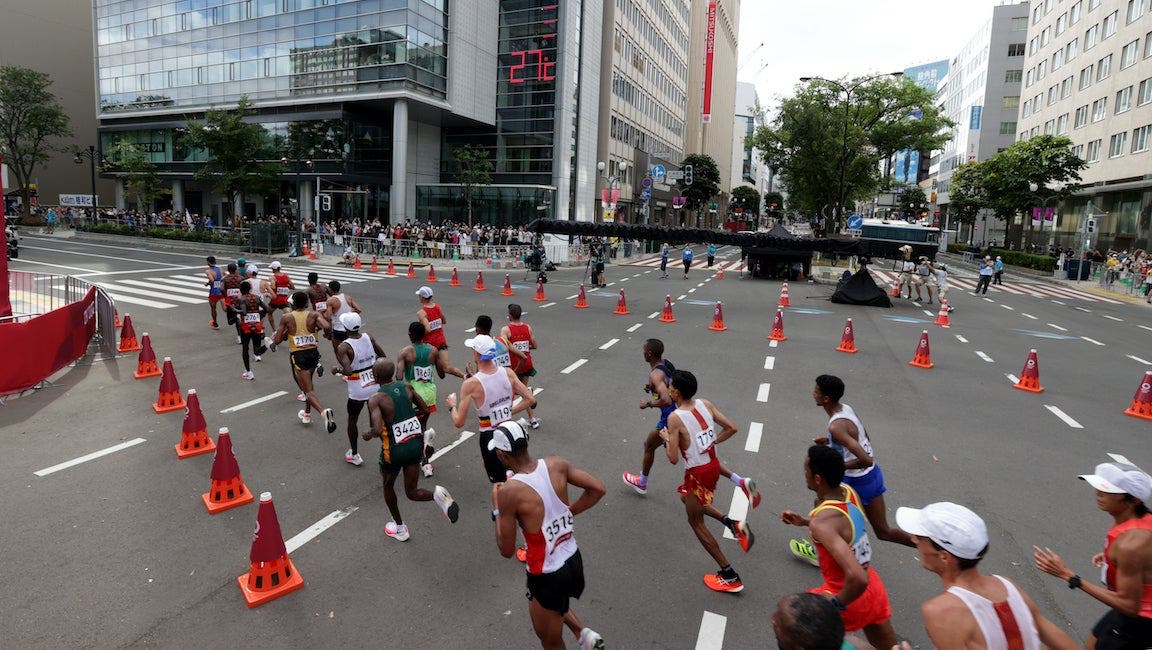 Men run on a city street cordoned off by traffic cones