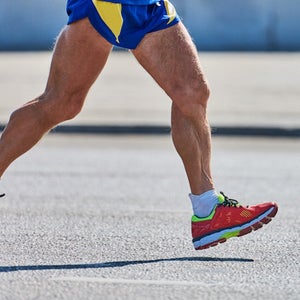 Older man jogging in sportswear on city road, heel striking.