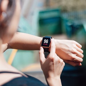 Over the shoulder view of a young woman wearing smart watch, using fitness app to check her training progress.