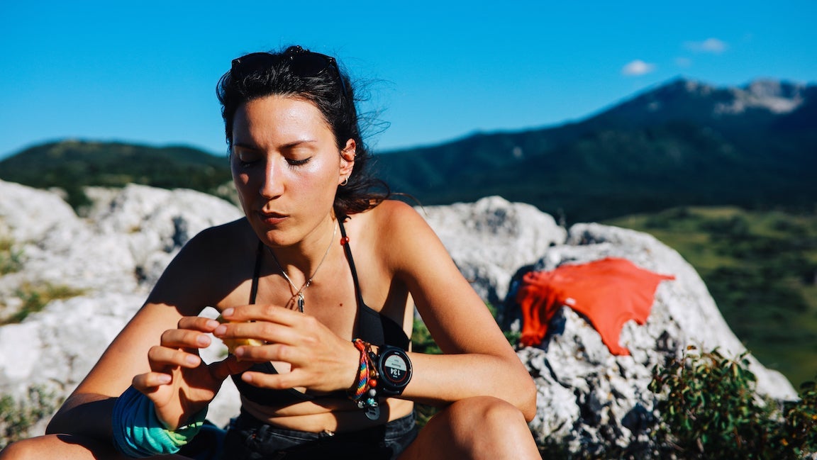 Woman hiking in the great outdoors, in the Dynamic Alps in Southern Europe. She is taking a short break, eating an apple for some extra energy.