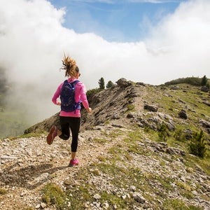 A woman trail running on top of a mountain.