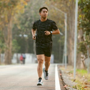 Guy jogging and checking smart watch between workout jogging outdoors.