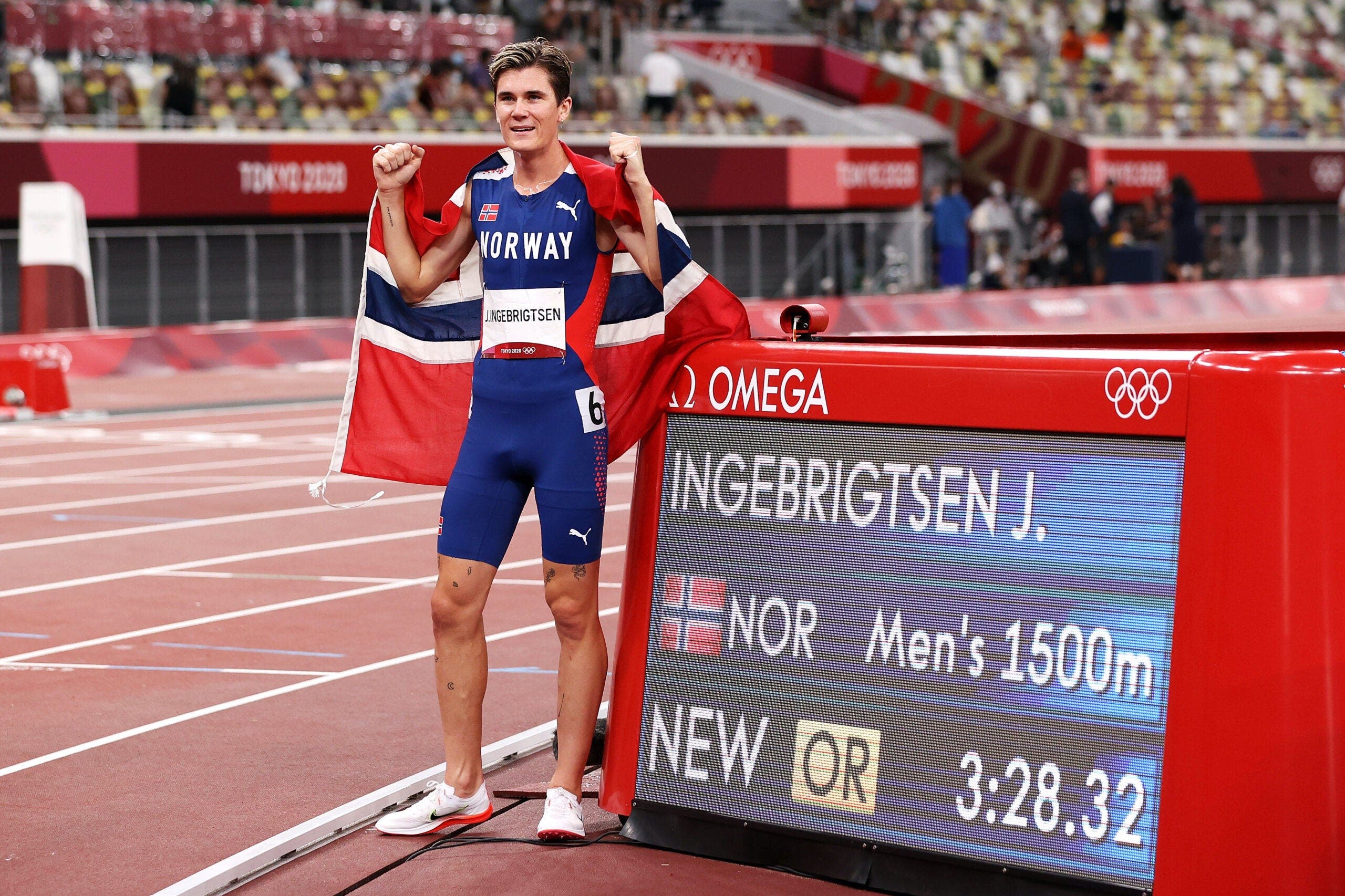 Jakob Ingebrigtsen posing with Norway flag next to his Olympic winning time in the 1500.