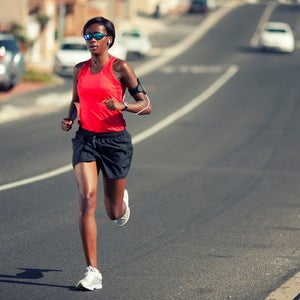 Woman running in sunglasses down a street in hot weather.