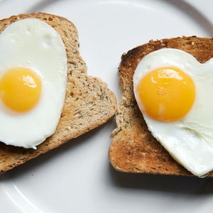 Pair of fried eggs in the shape of hearts on two pieces of toast on a plate