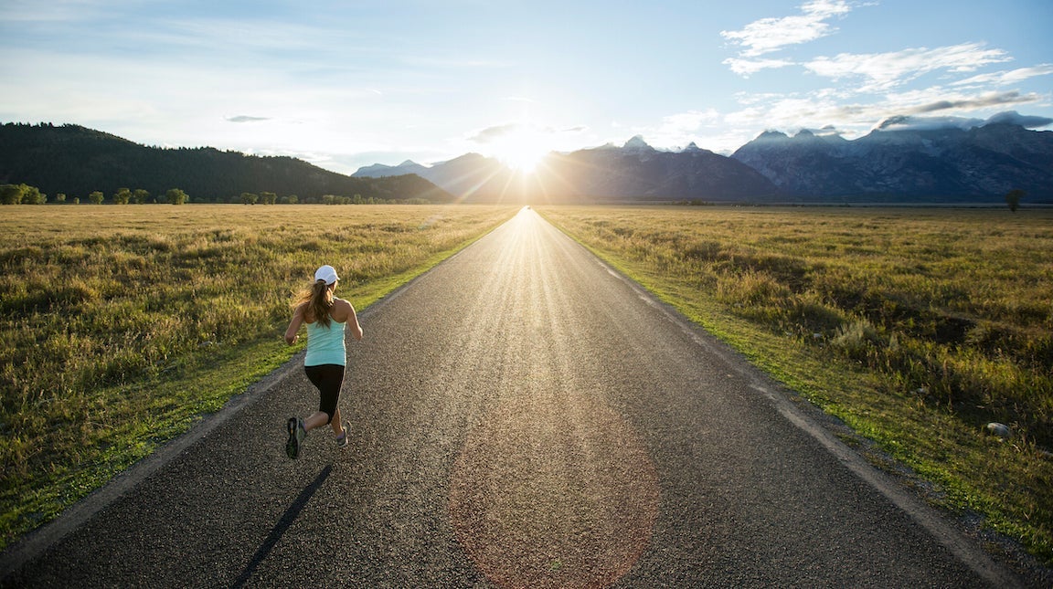 A woman running near the Teton mountains in Jackson Hole, Wyoming.