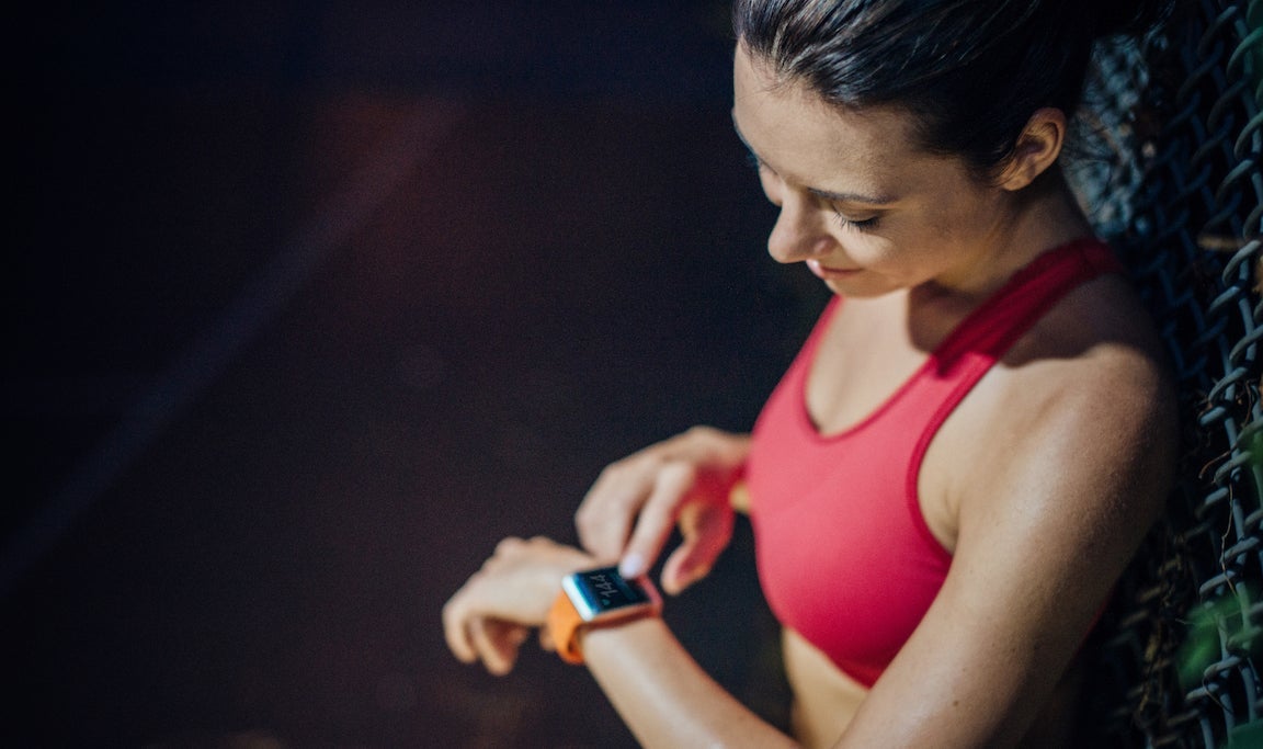 Woman checking pulse with smartwatch after a run.