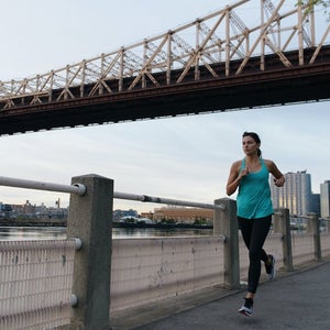 Woman running under NYC bridge.
