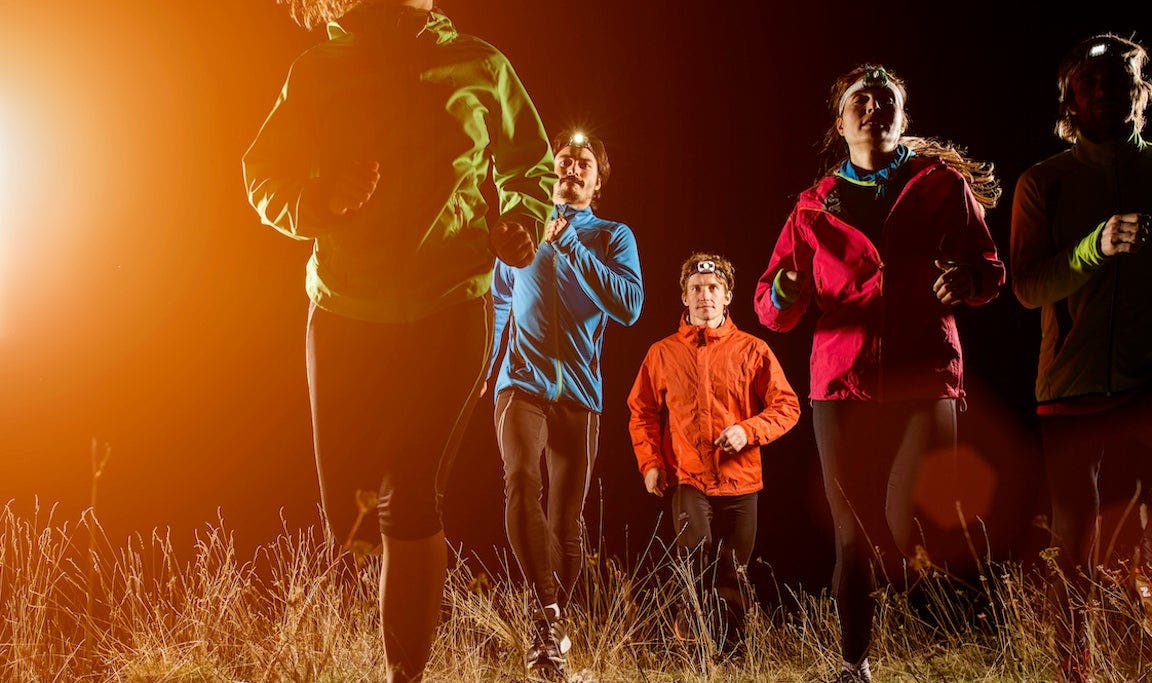 Joggers running on field at night