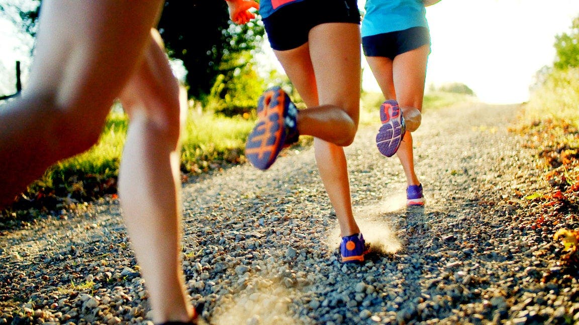 Women running up gravel road.