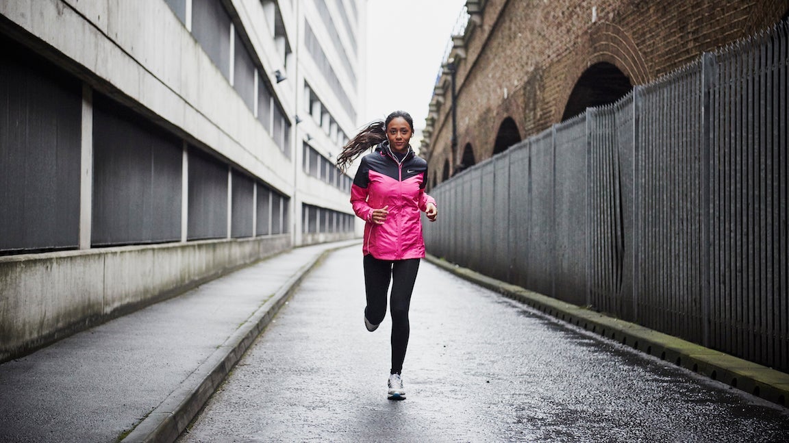 Female runner in pink rain jacket running in the city.