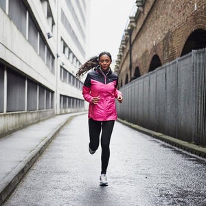 Female runner in pink rain jacket running in the city.