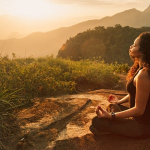 Young woman meditating on mountain top.