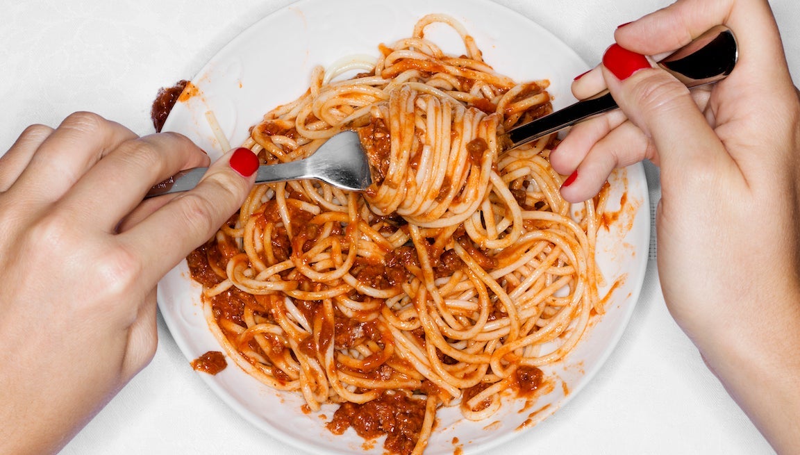 Female eating spaghetti, overhead view.