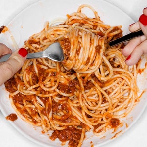 Female eating spaghetti, overhead view.