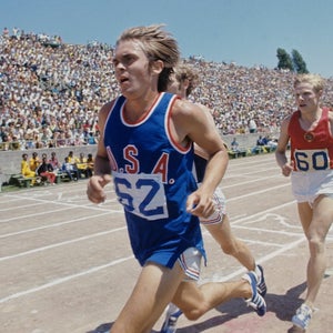 Steve Prefontaine racing in a blue uniform with a red USA on chest.