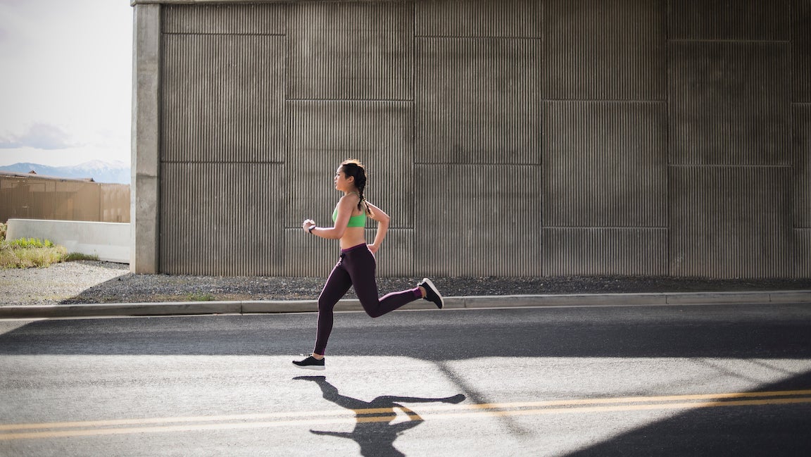 Young woman running under freeway overpass.