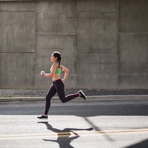 Young woman running under freeway overpass.