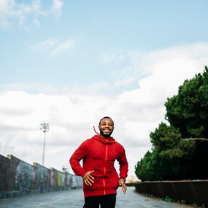 Portrait of young black guy in casual clothing, running on the street.