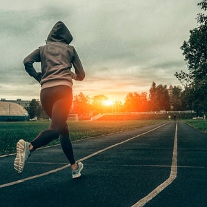 Women running on track as sun is setting.
