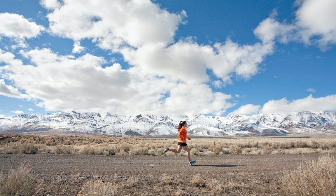 Woman running on rural road in mountains.