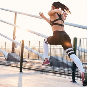 Young woman sprinting in the city over a bridge.
