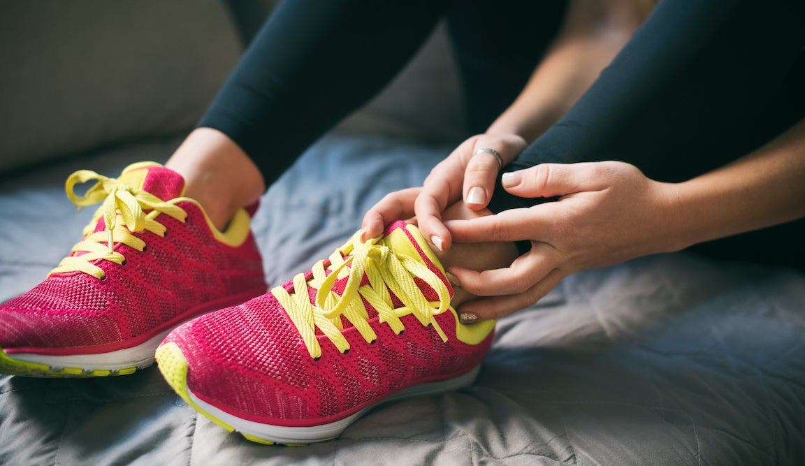 Young Sport Woman Holding Injured Ankle on bed.