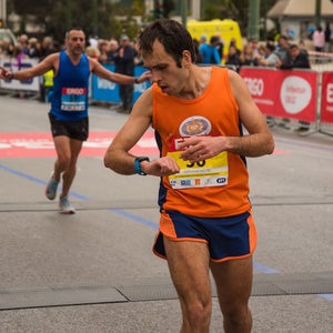 Participant looking at his watch to check the time it took to complete. Steady race pacing is key to marathon progression.