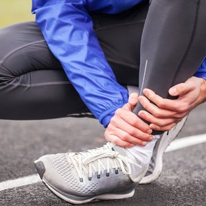 Cropped shot of a young man holding his ankle in pain while running.