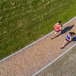 Aerial view of female joggers on woodchip trail.