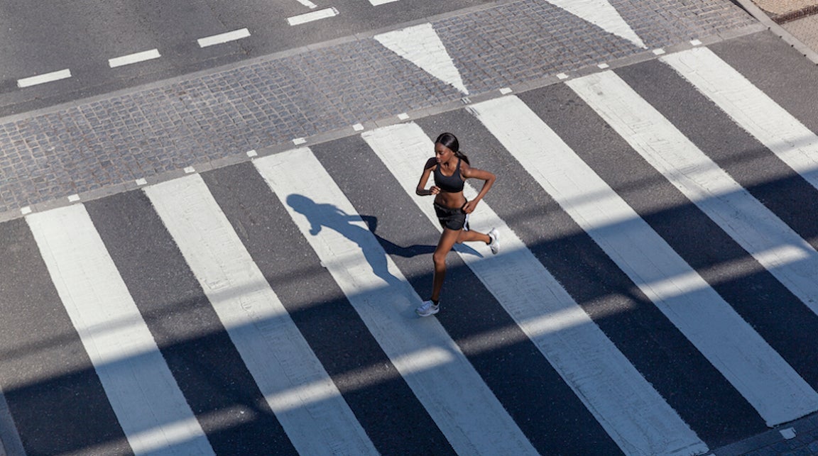 Young woman jogging on zebra crossing in a city.