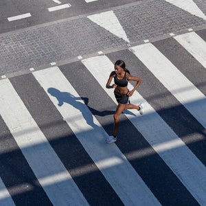 Young woman jogging on zebra crossing in a city.