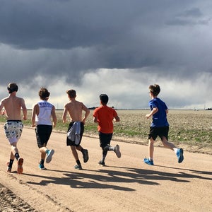 High school boys training group dirt road rain clouds