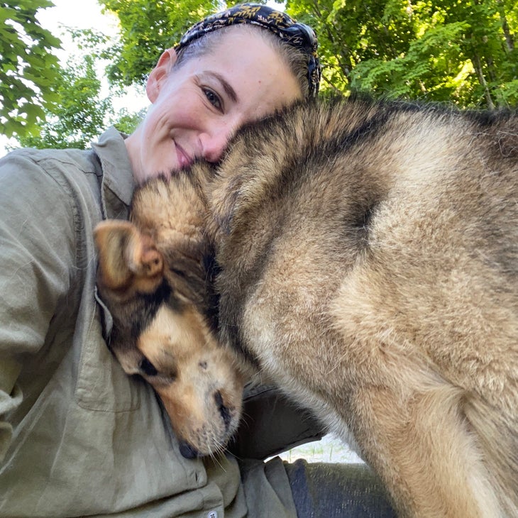 a woman cuddling a gray dog