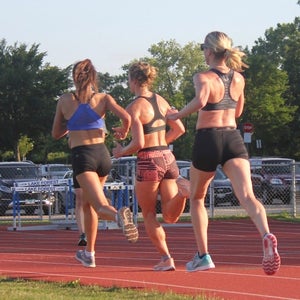 Three women doing a workout on the track.