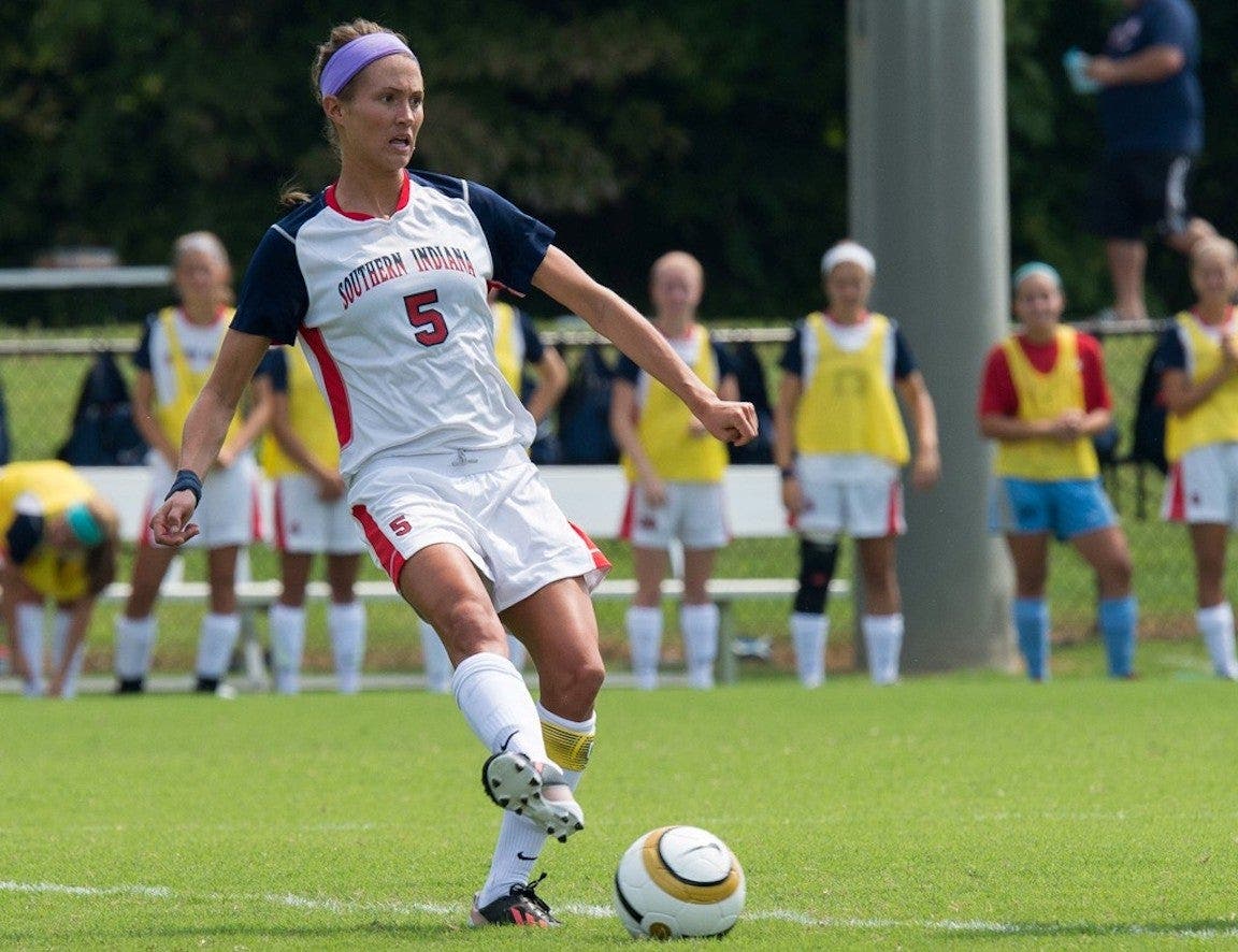 Soccer player in white uniform kicking ball during a game.
