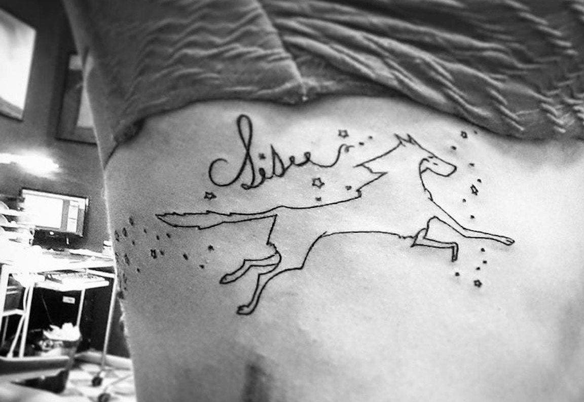A tattoo of the word Sisu scrawled above a wolf.