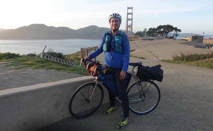 Man posing with bike with Golden Gate Bridge behind him.
