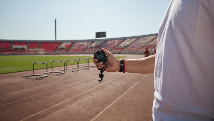 Coach measuring time with a stopwatch on a track.