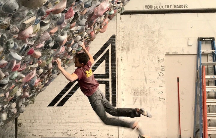 Teenage boy practicing rock climbing in a climbing gym.