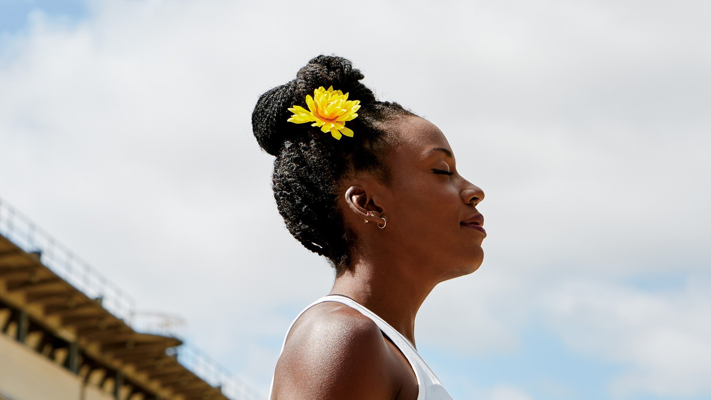 Profile of woman standing outside with a yellow flower in hair