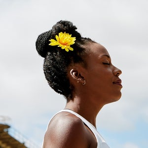 Profile of woman standing outside with a yellow flower in hair