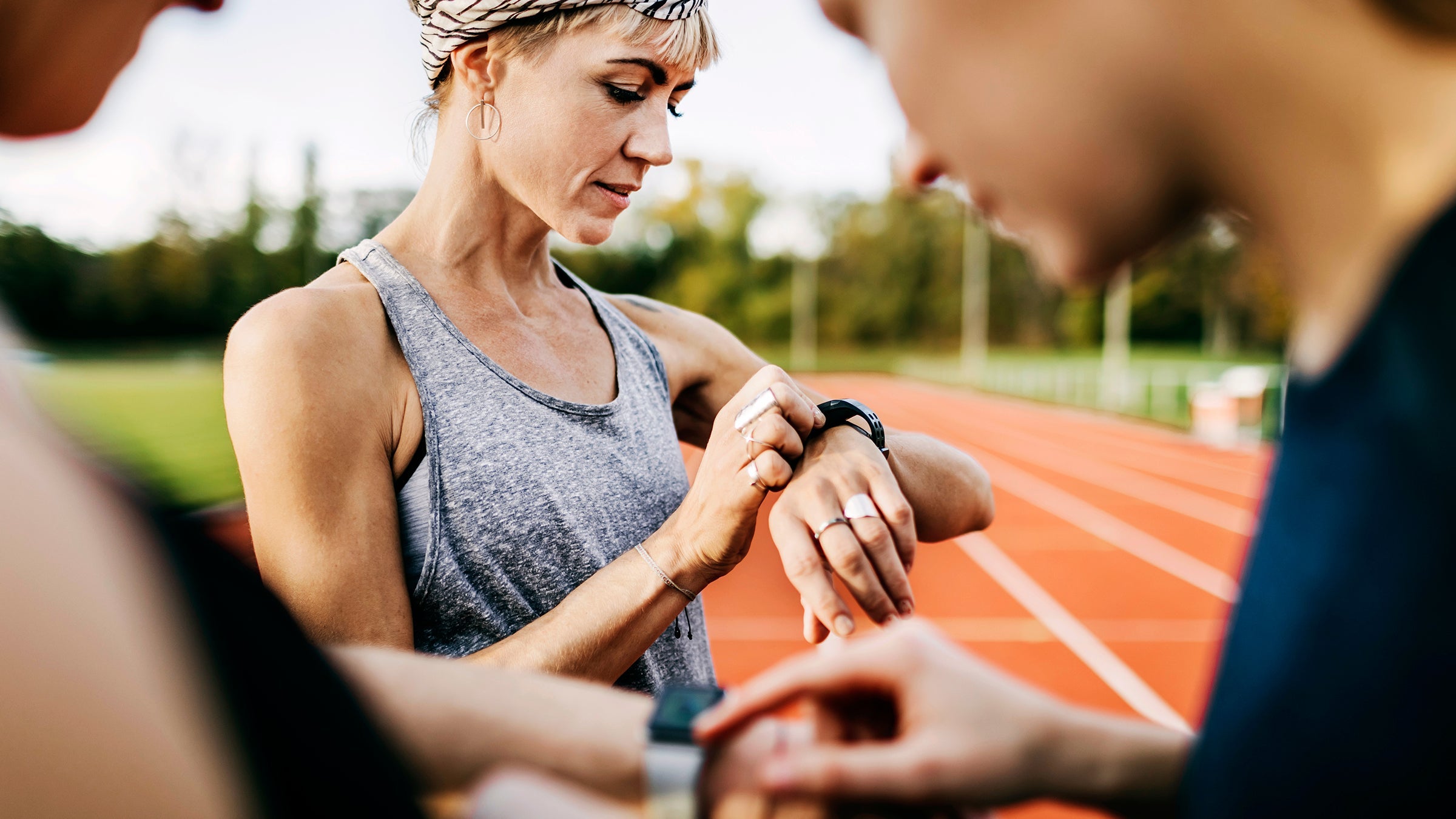 Runners checking their times after a speed workout on an outdoor track.