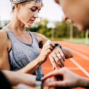 Runners checking their times after a speed workout on an outdoor track.