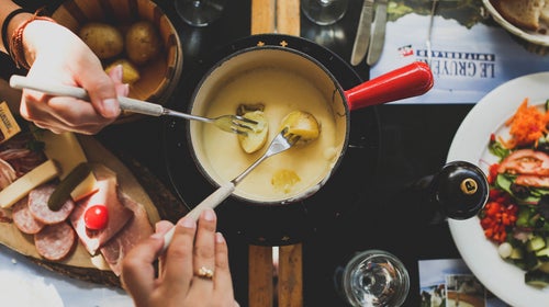 Dipping potatoes into a pot of fondue
