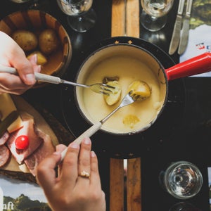 Dipping potatoes into a pot of fondue