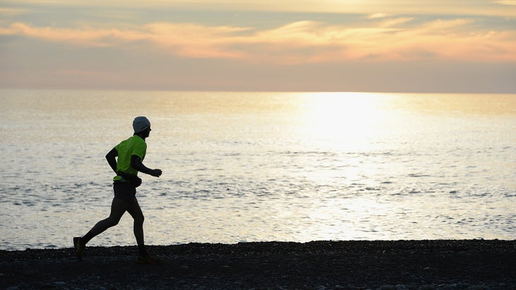 man running on beach at sunset