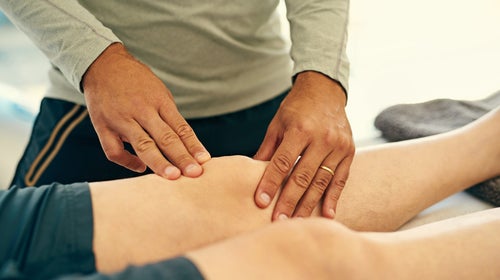 Physical therapist diagnosing knee